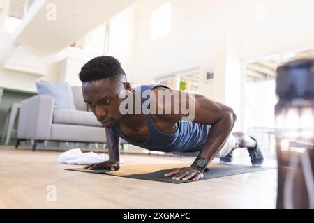 Focused african american man exercising at home, doing push ups. Fitness, training, exercise, domestic life and healthy lifestyle, unaltered. Stock Photo