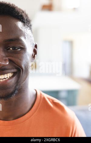 Half portrait of happy african american man in sunny kitchen smiling, copy space. Wellbeing, domestic life and lifestyle, unaltered. Stock Photo