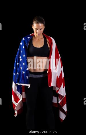 Athletic young Caucasian woman draped in an American flag, with copy ...