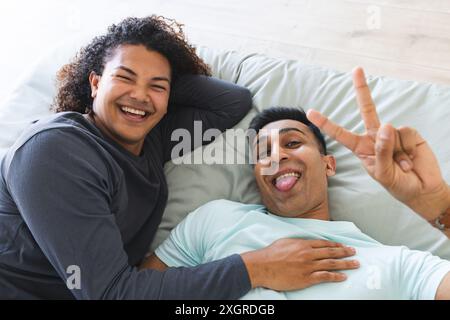 Gay biracial couple enjoys a playful moment at home. They're sharing a laugh, creating a sense of warmth and intimacy. Stock Photo