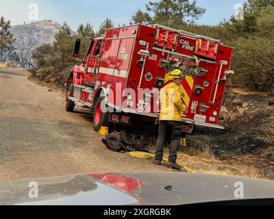 Santa Ynez, California, USA. 8th July, 2024. Cal Fire fireman roles up yellow fire house near Red fire truck on Figueroa Mountain Road, with ash covered mountain in the background, in the midst of the Lake Fire in Santa Ynez, California on July 8, 2024 (Credit Image: © Amy Katz/ZUMA Press Wire) EDITORIAL USAGE ONLY! Not for Commercial USAGE! Stock Photo