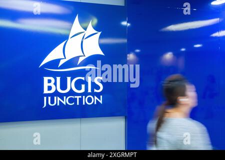 A lady walk pass Bugis Junction logo in slow motion, blue colour scheme. The mall is managed by CapitaLand Group. Singapore. Stock Photo