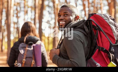 Happy black guy looking aside, hiking with girlfriend Stock Photo