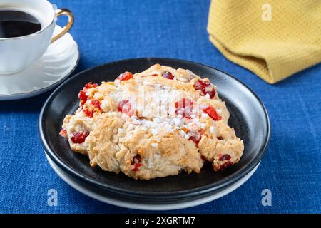 A fresh traditional large, English, Cherry Rock cake served with a cup of black coffee. The cakes are plated on a plain table cloth Stock Photo