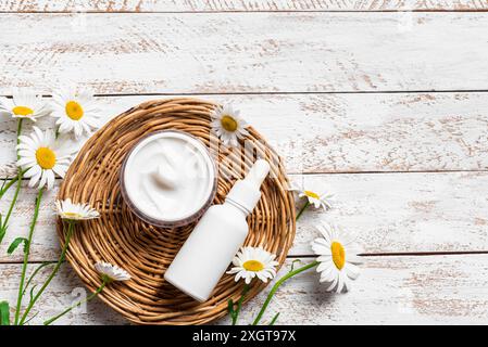 Natural organic cosmetics with chamomile flowers on white wooden background, top view, copy space. Beauty cream and face serum with white daisies, org Stock Photo