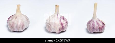 Three unpeeled fresh bulbs of garlic on a white isolate background. Stock Photo