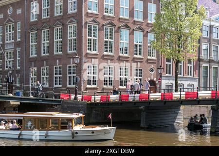 Boats pass under bridges over a canal on a sunny day in Amsterdam, The Netherlands. Stock Photo