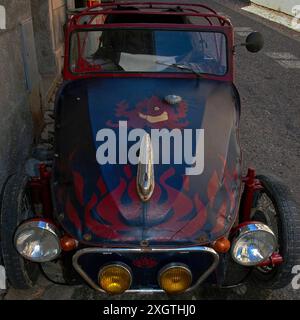 A Velorex Oskar, parked in Tábor, South Bohemia, Czechia, in 2006.  Oskars were tubular steel-framed three-wheeler cars, covered in interchangeable leather-like vinyl panels, held in place by turn buttons.  They were made in the former Czechoslovakia from 1942 - 1971. This Oskar has been customised with a demon and flames of hell design on the bonnet or hood.  The chrome fuel filler cap can be seen next to the red demon. Stock Photo