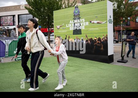 Members of the public and an ad hoarding at Wimbledon station in the second week of the All England Lawn Tennis Association's championship, on 9th July 2024, in London, England. Stock Photo