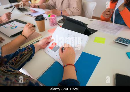 A diverse team collaborates in a business office setting, analyzing financial charts and discussing strategic plans, highlighting teamwork and detaile Stock Photo