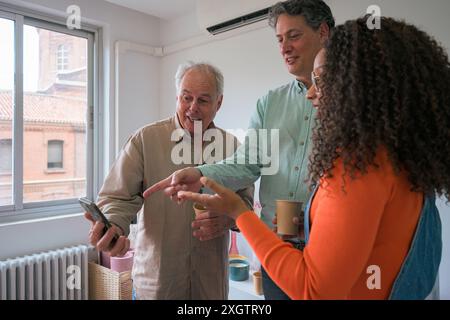 Three colleagues are actively engaged in an informal business discussion in a well-lit office space, demonstrating teamwork and collaboration Stock Photo