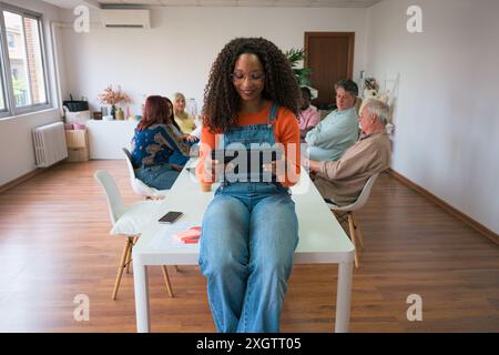 A diverse team engaging in a casual business meeting within a bright, modern office space The focus is on a young woman using a tablet Stock Photo