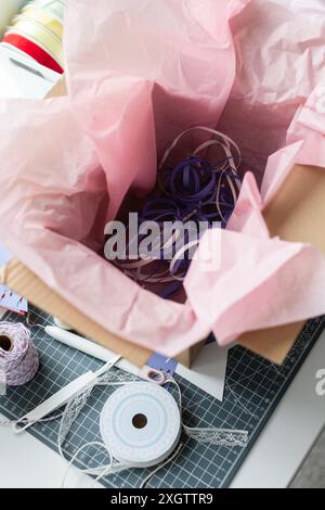Photo of a young woman's workspace filled with colorful paper and ribbon as she engages in intricate paper crafting, showcasing creativity and artistr Stock Photo