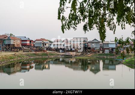 Stilt homes built on the riverbank, reflecting cultural architecture in a small, serene Cambodian village. Stock Photo