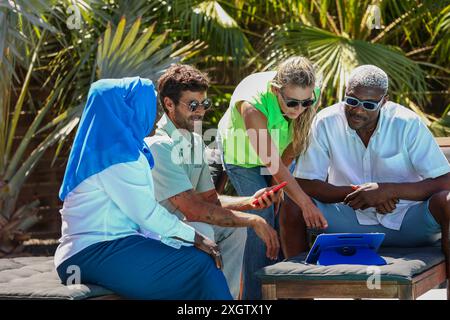 A diverse focused team of four colleagues, including a Muslim woman in hijab, Hispanic, Asian, and African American, engage in a business meeting outd Stock Photo