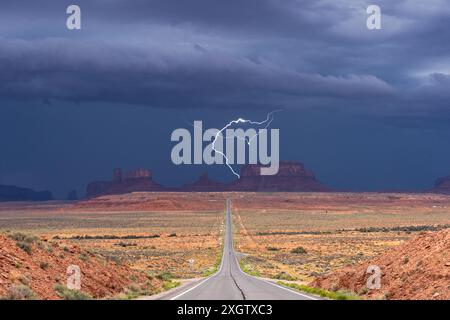 A dramatic scene capturing a lightning bolt striking over Monument Valley, Arizona, with a dark, stormy sky looming above the iconic red rock formatio Stock Photo