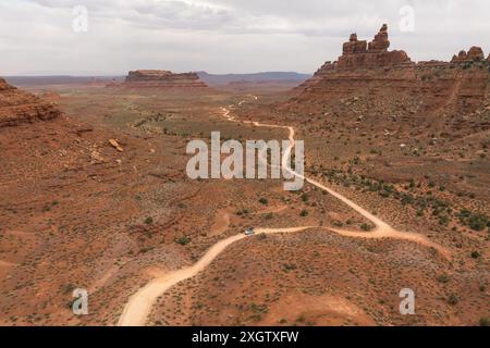 Aerial view of a winding dirt road cutting through a lush green forest ...