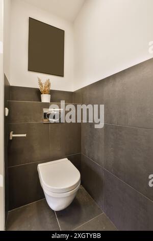 This image showcases a stylish modern bathroom with a wall-mounted toilet and dark gray tiles, located in Henkenshage, Amsterdam Stock Photo