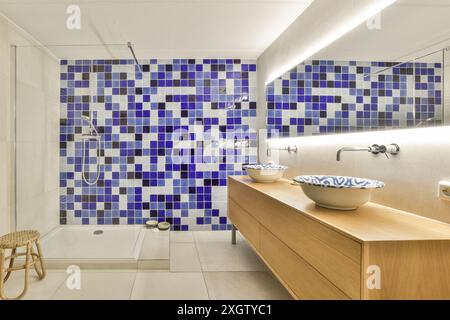 Contemporary bathroom featuring blue and white mosaic-tiled walls and a wooden vanity in Herentalsstraat, Amsterdam, Netherlands The space includes a Stock Photo