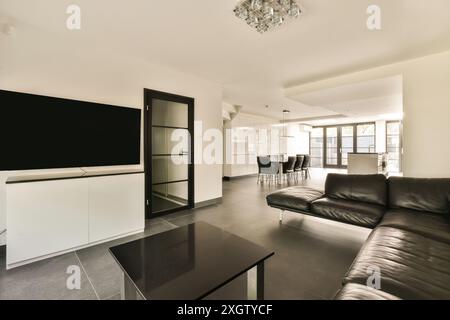 This spacious apartment on Hilversumstraat, Amsterdam features a sleek modern interior with a large black leather sofa, a stylish white entertainment Stock Photo