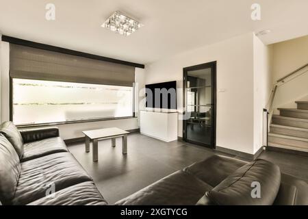 A stylish modern living room featuring a large window, sleek furniture, and minimalistic decor in a house located in Hilversumstraat, Amsterdam, Nethe Stock Photo