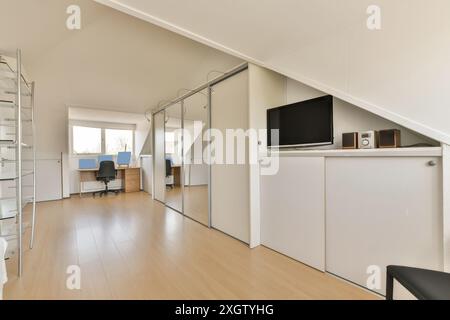 Bright and spacious home office located in Jan Weilandlaan, Netherlands, featuring sleek white storage cabinets, laminate wood flooring, and multiple Stock Photo