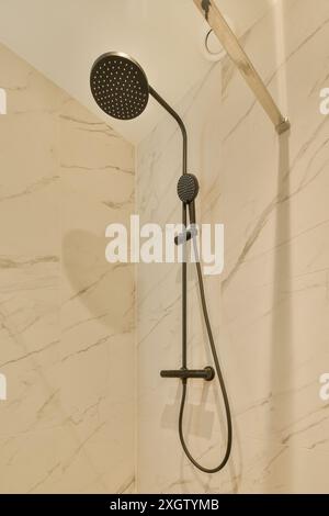 A shower that is in a bathroom with marble walls and white tiles on the wall behind it, there is a hand held shower Stock Photo