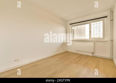 A bright and empty room featuring wooden floors and a large window with decorative grills, located at Amerbos 106 Stock Photo