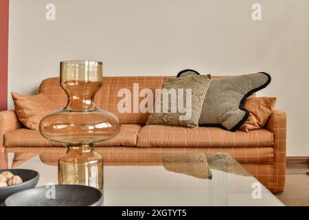 Contemporary living room interior showcasing a stylish caramel leather sofa adorned with decorative pillows, complemented by a glossy reflective coffe Stock Photo