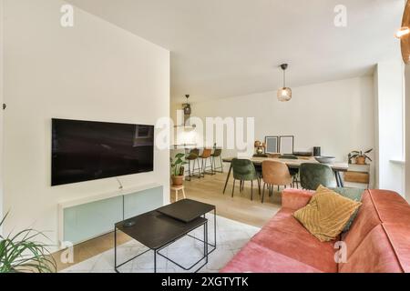 Stylishly furnished living room with a red sofa, mounted TV, and a workspace in a contemporary interior. Stock Photo