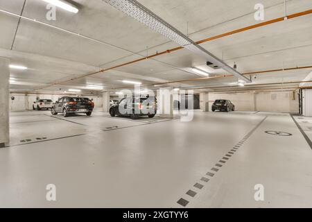 Modern underground car park interior with clearly marked spaces and multiple parked vehicles, featuring bright lighting and clean lines. Stock Photo