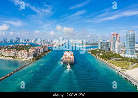 Large Container Ship Entering Harbor and Miami City on Sunny Day, USA. Aerial View. Stock Photo