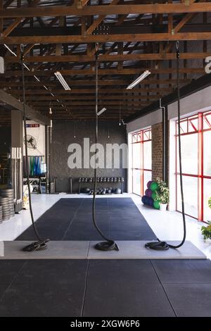 A well-equipped gym interior showcases various fitness equipment. The space is designed for functional training with ropes, weights, and exercise ball Stock Photo