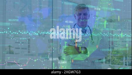 Financial data processing over world map against caucasian senior male doctor smiling at hospital. Medical healthcare and technology concept Stock Photo