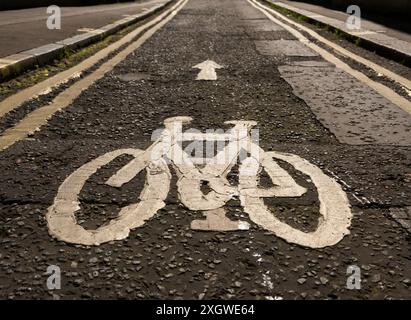 Bicycle lane marked by the symbol of a bicycle painted on the road with double yellow lines restricting car parking and unloading Stock Photo