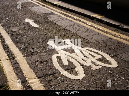 Bicycle lane marked by the symbol of a bicycle painted on the road with double yellow lines restricting car parking and unloading Stock Photo