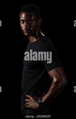 African American man poses confidently on a black background, with copy ...