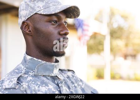 Thoughtful african american male soldier in uniform standing outside home, copy space. Military service, army, home, domestic life and lifestyle, unal Stock Photo