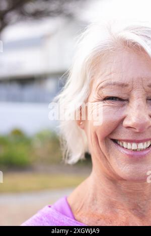 Vertical half portrait of happy senior caucasian woman with white hair smiling outdoors, copy space. Wellbeing, health and active senior lifestyle, un Stock Photo