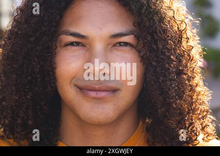 Close-up of a young biracial man outdoors, unaltered. His confident smile and casual style suggest a relaxed, sunny day. Stock Photo