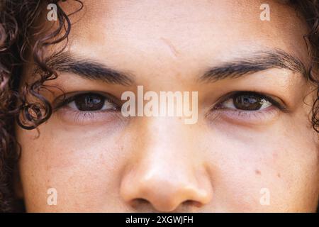 Close-up of a young biracial man's eyes and face, unaltered. His gaze is captivating, highlighting the beauty of diverse features. Stock Photo