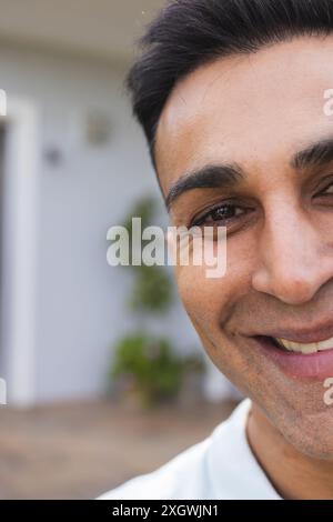Close-up of a smiling Middle Eastern man outdoors, unaltered. His cheerful expression adds warmth to the home setting. Stock Photo