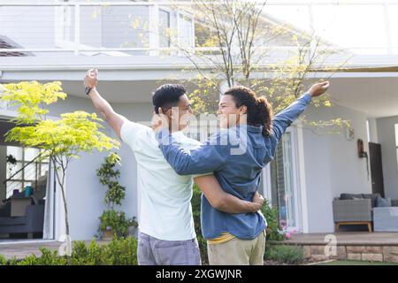Middle Eastern man and young biracial man embrace joyfully outdoors. Their warm hug signifies a celebration or a heartfelt reunion at home. Stock Photo