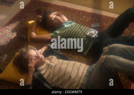 High angle view of two boys lying on colorful rug, one with hands on face, other with vintage music player Stock Photo