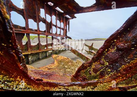 Rusty Shipwreck Remains on Sandy Beach Viewed from Inside Stock Photo