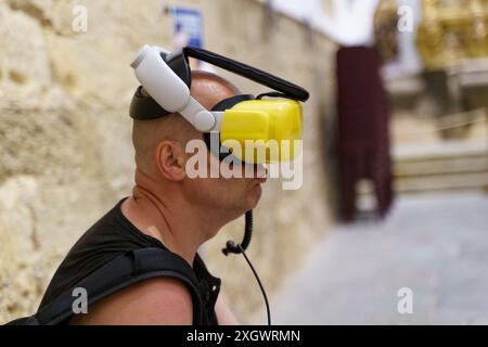 Astorga, Spain - June 4, 2023: A man wearing a VR headset sits in a museum, experiencing virtual reality. The museum is in the Cathedral of Santa Mara Stock Photo