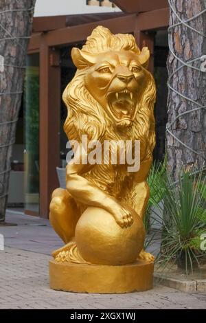 Gold lion statue with paw placed on a golden sphere.  Outside a hotel in Italy. Stock Photo