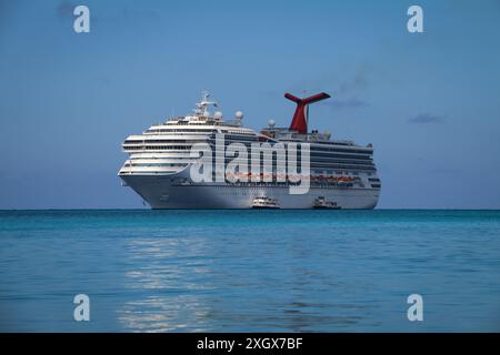 A Caribbean cruise ship docked in the ocean off the shore of Nassau City on a sunny day, The Bahamas Stock Photo