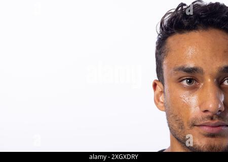 Close-up of a young biracial man, with copy space, on a white background. His expression suggests contemplation or concern, set against a neutral back Stock Photo