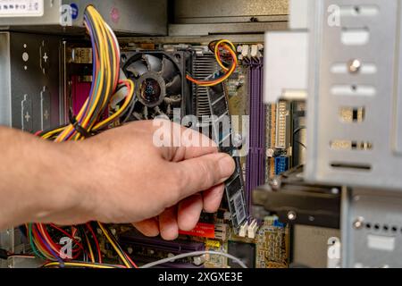 Technician installing a RAM bank into a computer. Stock Photo
